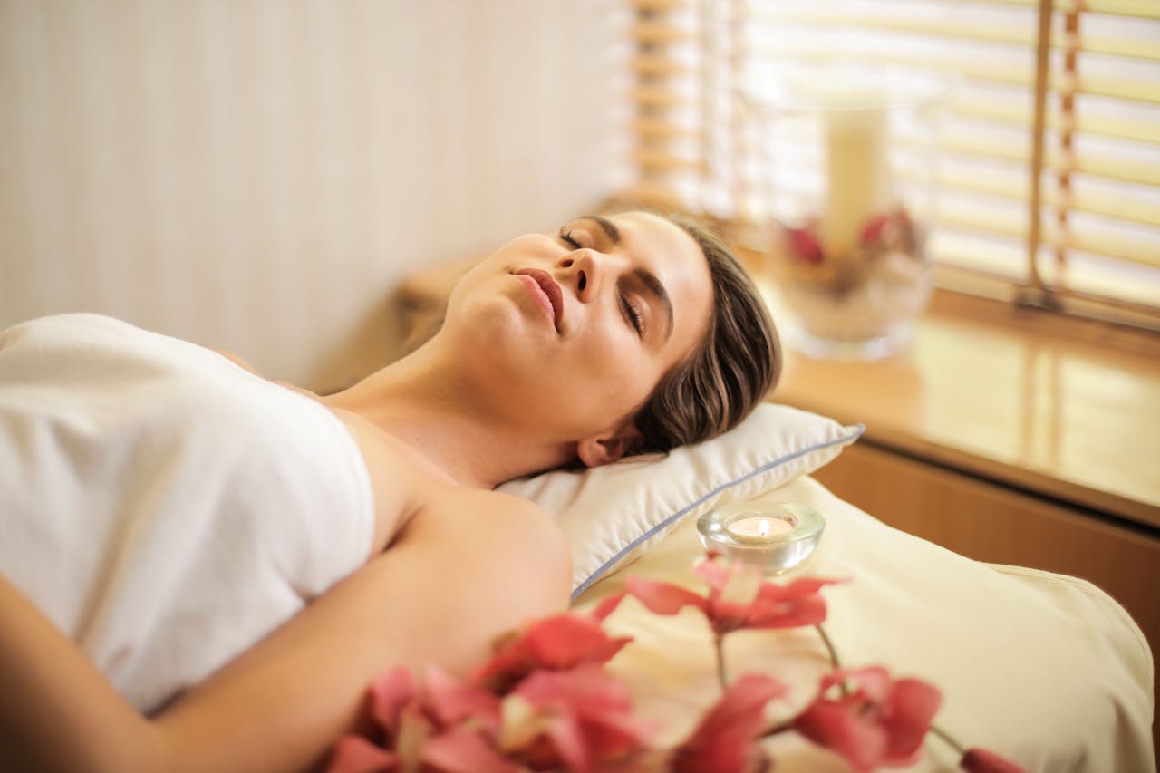 services-03 Woman enjoying a relaxing spa day with flowers and candles indoors.